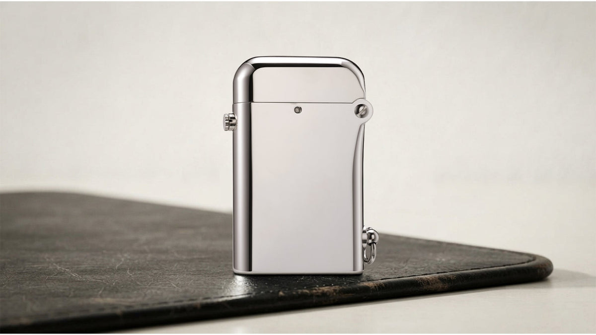 Closed polished silver lighter with side lever on a dark tabletop