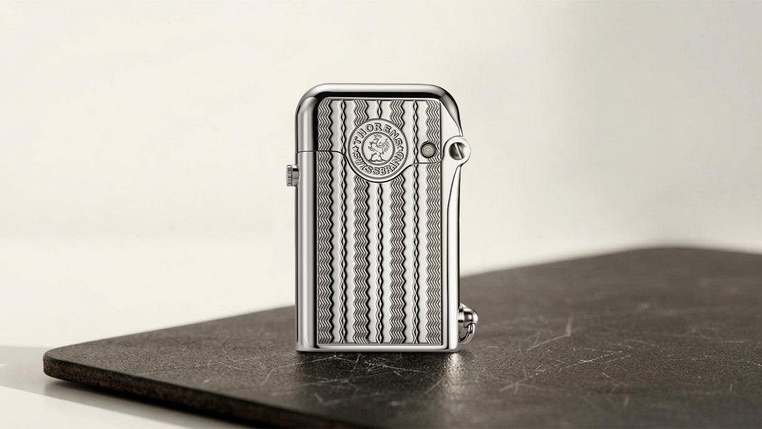 Silver THORENS mechanical lighter with ridged front on a dark tabletop