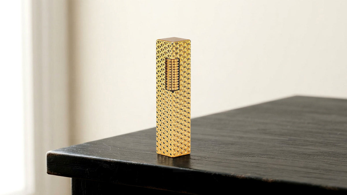 Closed gold lighter with dotted texture on a dark tabletop