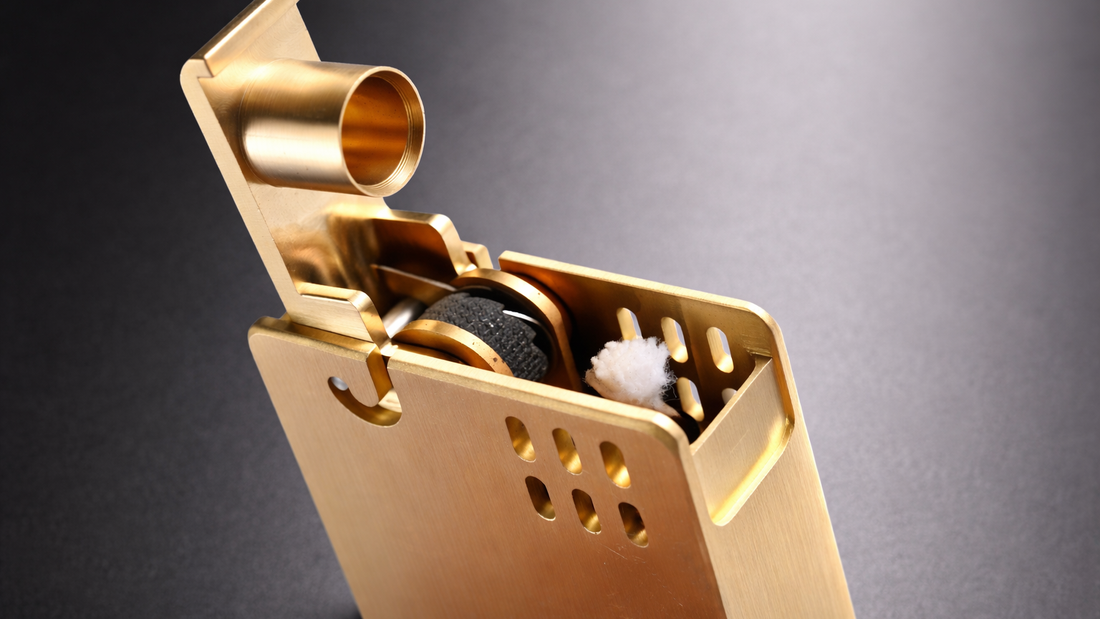 Glossy brass minimalist fluid lighter showing internal wick and flint wheel mechanism with smooth undecorated brass construction