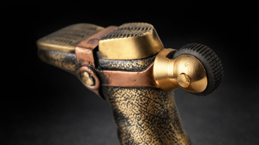 Solid brass boot and helmet fluid lighter with heel-mounted roller wheel and hidden pull-to-ignite design