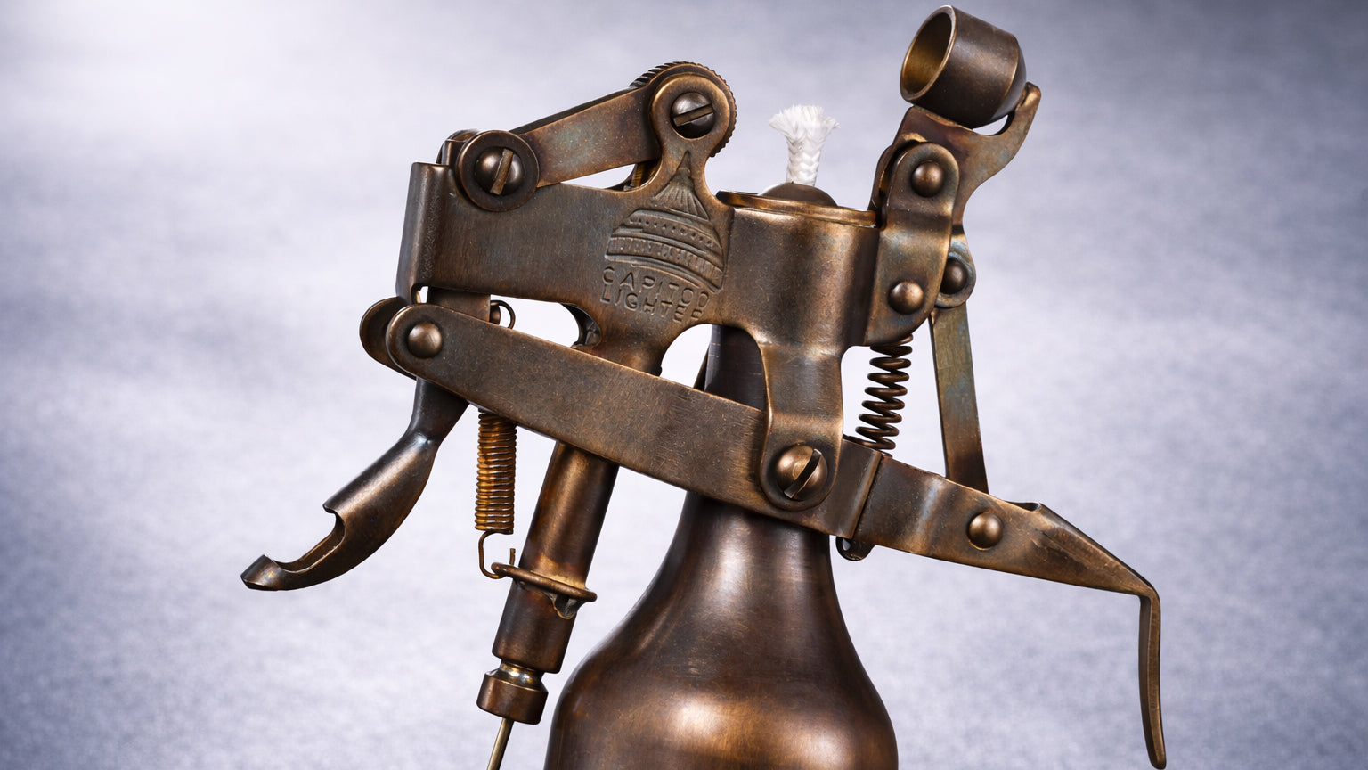 Mechanical brass table lighter with exposed fluid system and articulated metal structure