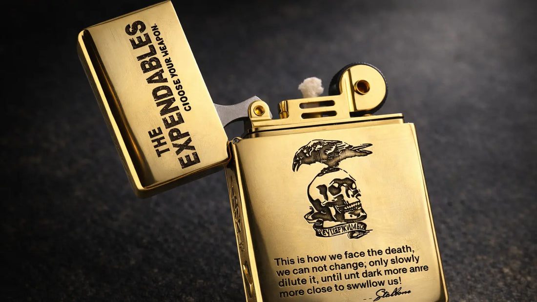 Close-up detail of The Expendables etched brass refillable fluid lighter with raptor and skull engraving on a dark textured background