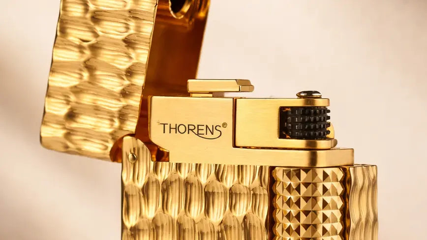 alt="Close-up of a crater-textured solid brass fluid lighter with side-slip ignition, showing the upper mechanical details"