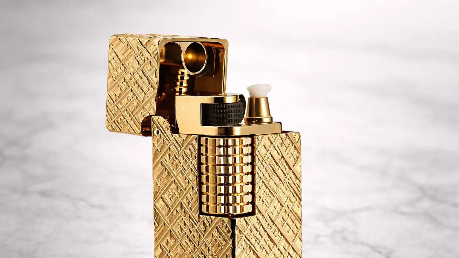 Gold side slip rectangular fluid lighter with engraved brass body and open lid, highlighting mechanical ignition details