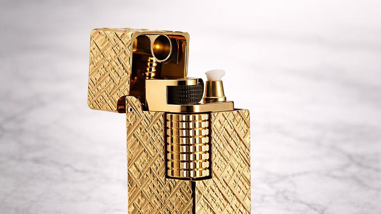 Gold side slip rectangular fluid lighter with engraved brass body and open lid, highlighting mechanical ignition details