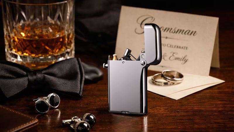 Silver THORENS lighter styled as a groomsman gift with whiskey glass, bow tie, cufflinks, wedding rings, and invitation card on a wooden table