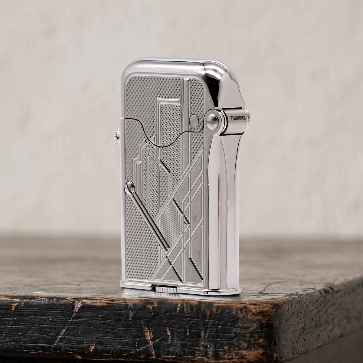 THORENS Gen 7 - Single Claw - TELEFLAM - Silver Metropolis lighter with Art Deco engraving and exposed mechanical ignition on tree bark.