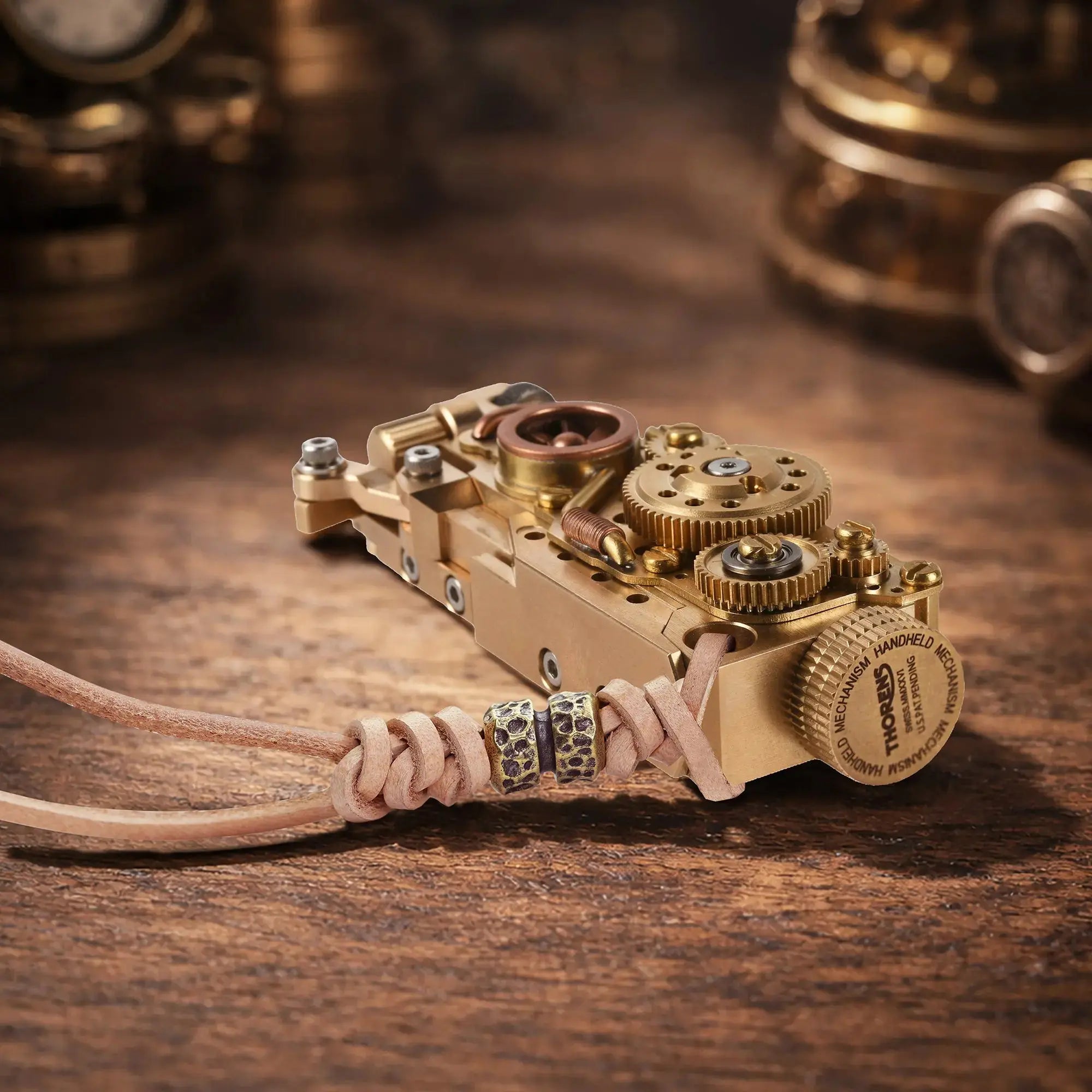 Thorens steampunk mechanical grip grand gear lighter in brass finish resting horizontally on a warm wood surface, featuring oversized exposed gear detailing, layered brass construction, and a leather lanyard with bead accents