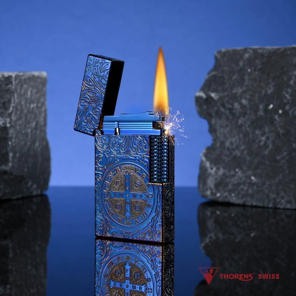 A lit Constantine Midnight Blue Sigil lighter showing a vibrant flame and sparks against a blue backdrop with textured stone elements.