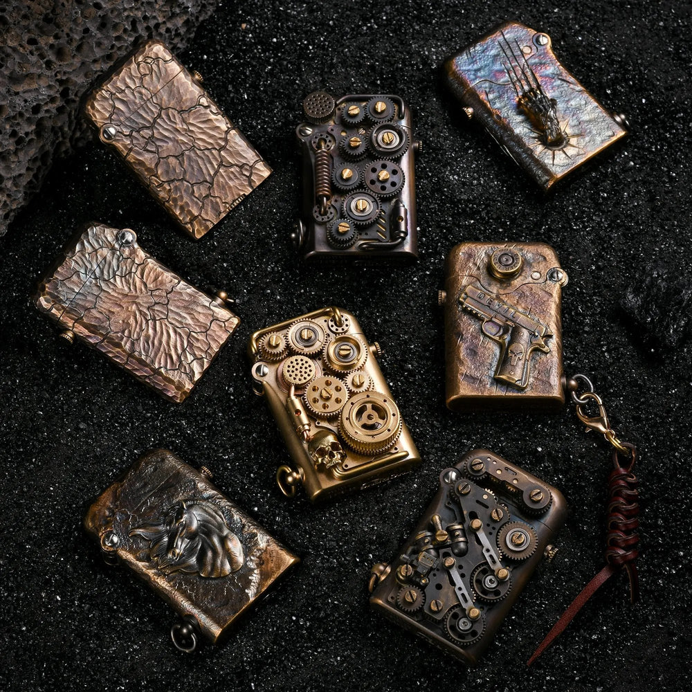 A curated selection of Gen 1 Single Claw lighters, including the hand-carved Earth Fissure models, steampunk gear designs, and relief sculptures, displayed on black volcanic sand.