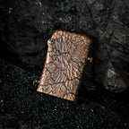 A Gen 1 Single Claw lighter with a hand-carved Earth Fissure texture, resting on black volcanic sand against a dark, craggy rock backdrop.