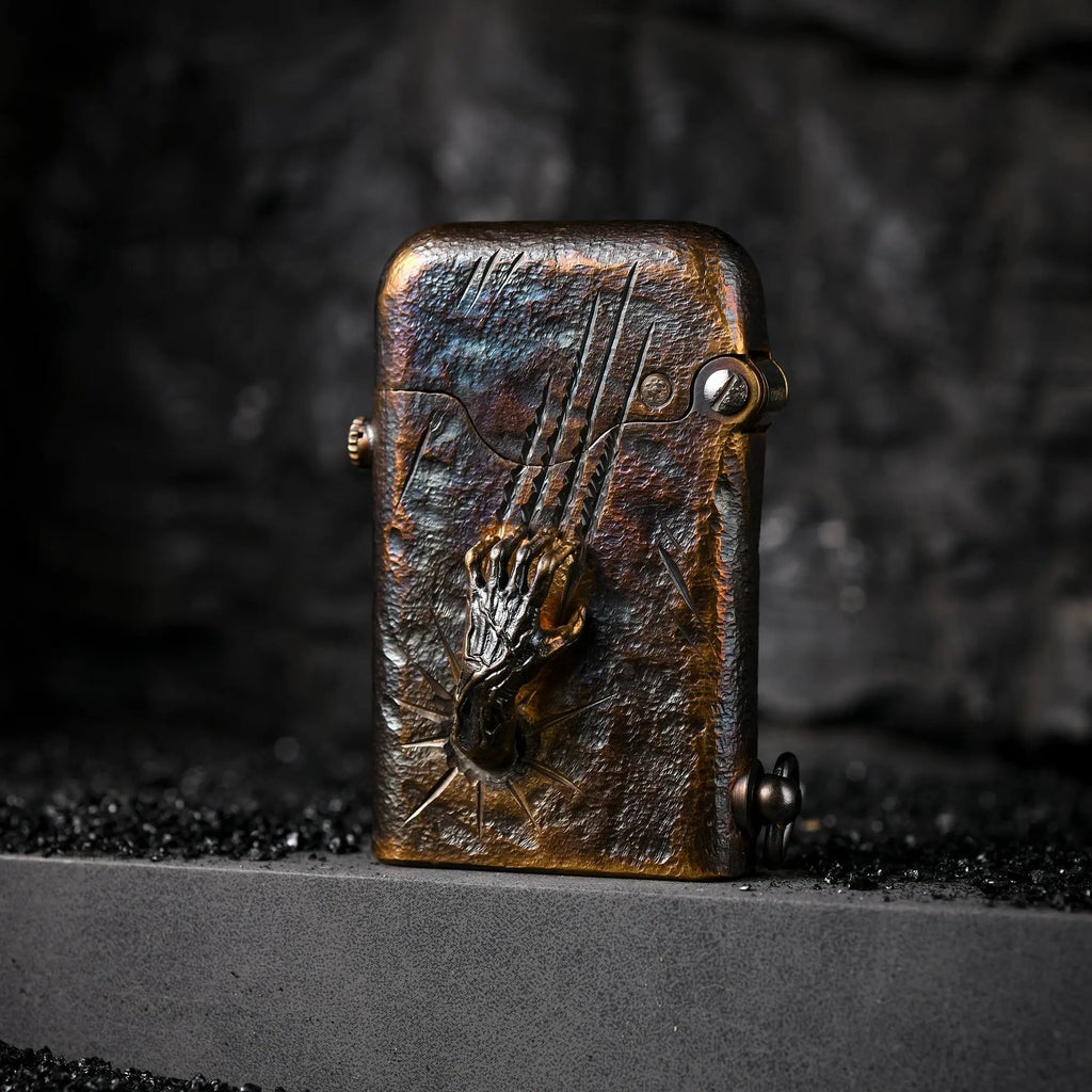 A Gen 1 Single Claw Spirit Claw lighter featuring a detailed skeletal hand relief and weathered brass texture, standing on a dark stone surface.