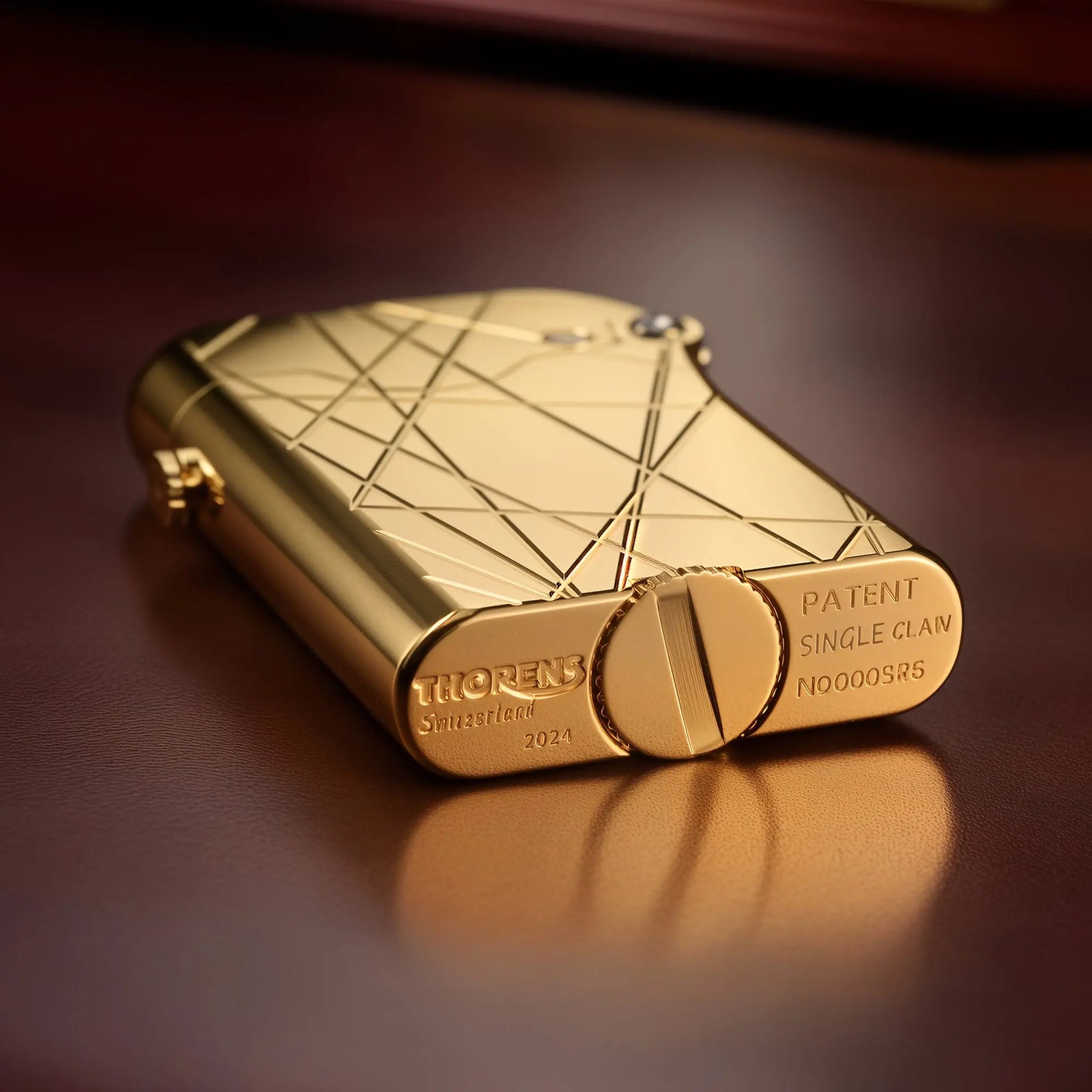 A gold-finished Thorens Gen 3 Single Claw lighter featuring a modern grid pattern, lying on a brown leather surface to show its base craftsmanship.
