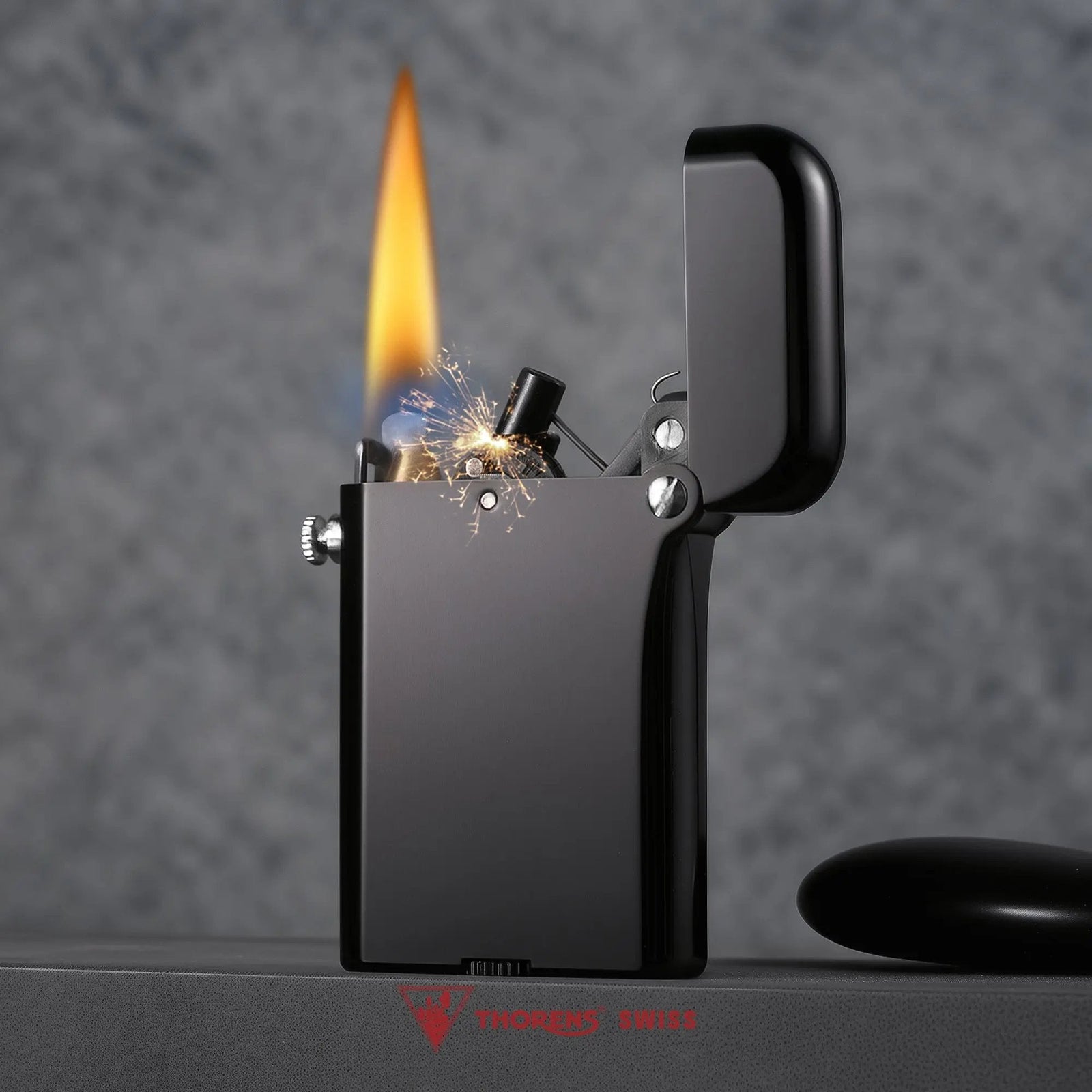 A Gen 4 Double Claw lighter with a glossy black finish shown ignited, capturing the mechanical sparks and flame of the Thorens bottom fill mechanism.