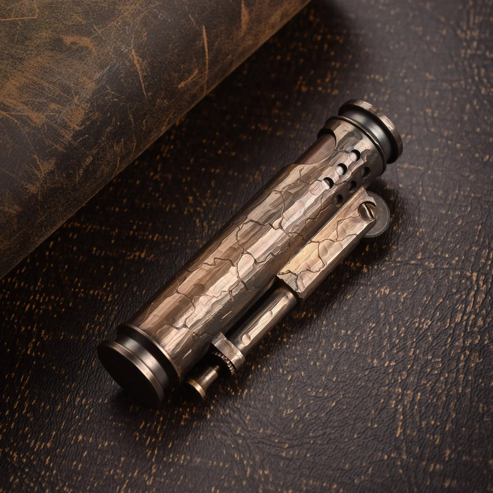 A cylindrical Battle Soul trench lighter featuring hand-carved cracks and a weathered brass finish, resting on a rustic dark leather surface.