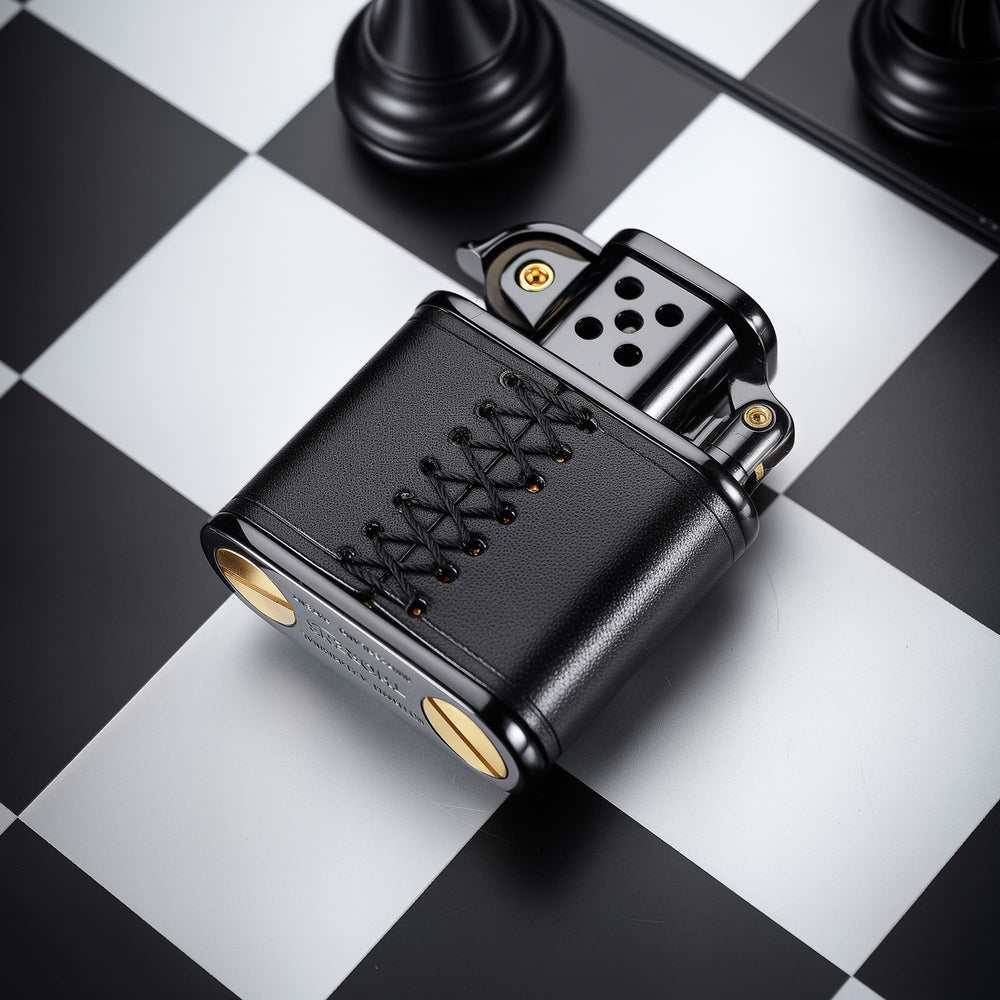 Back view of the hand-stitched black leather lighter, showing the black leather wrap and hand-stitched lace detail on a chessboard-style background.