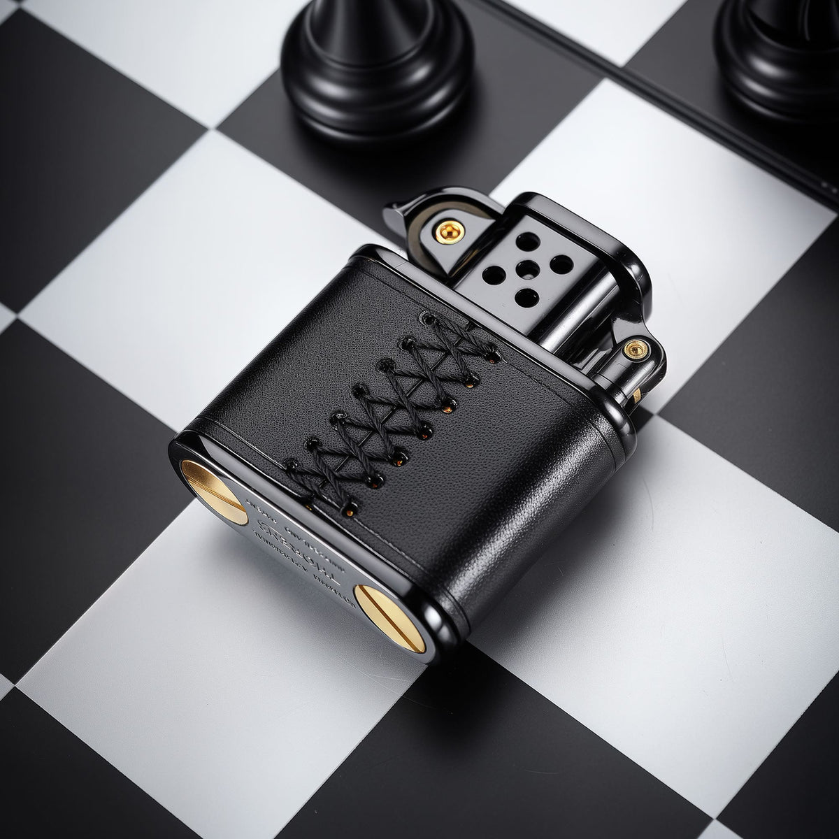 Back view of the hand-stitched black leather lighter, showing the black leather wrap and hand-stitched lace detail on a chessboard-style background.