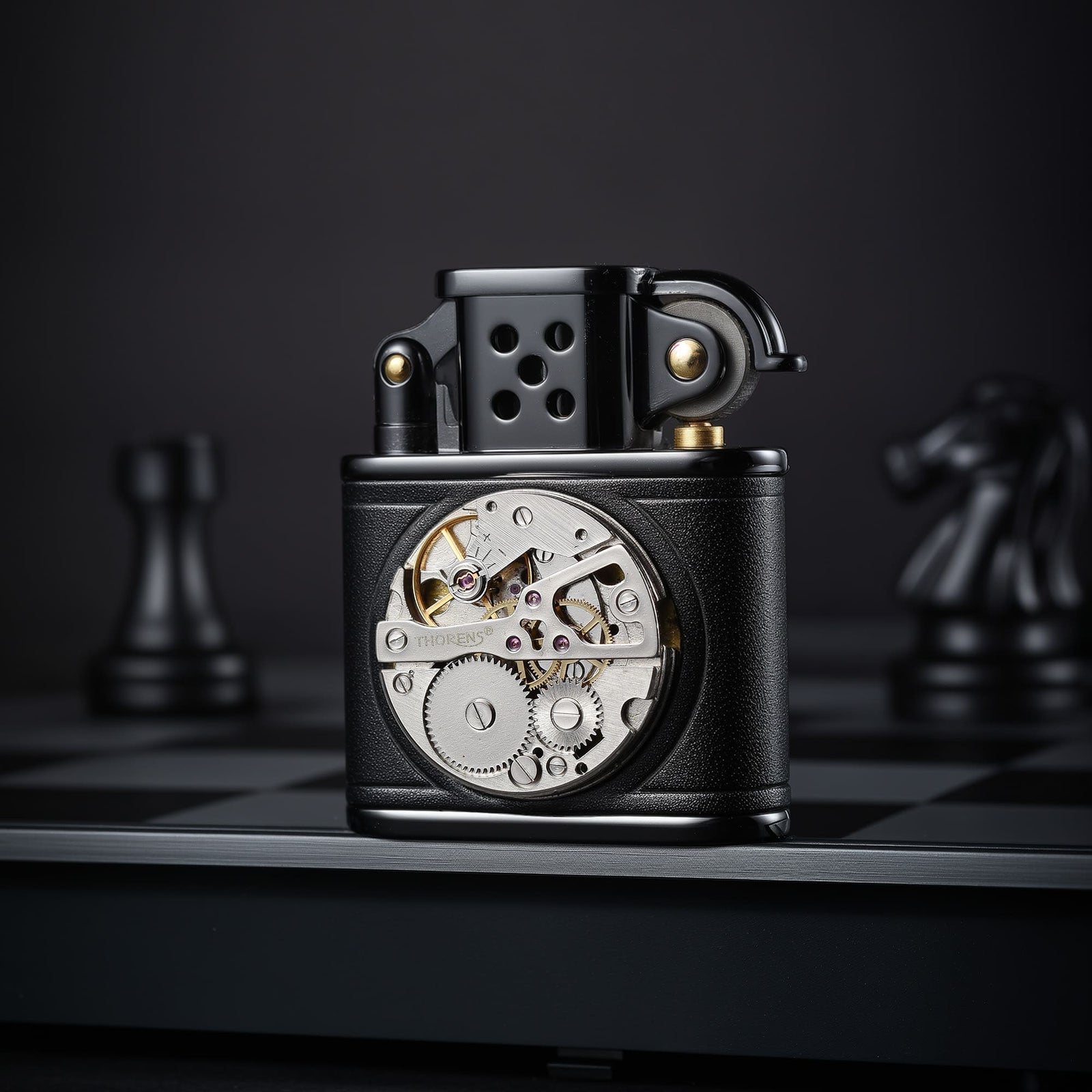 Front view of the hand-stitched black leather lighter with inlaid mechanical movement, displayed on a dark chessboard-style background.