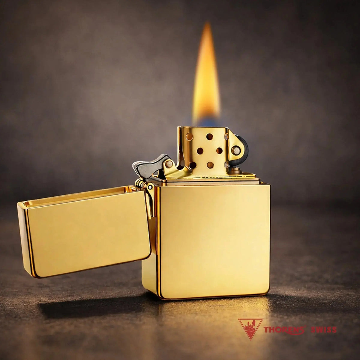 A cinematic shot of a gold-finish Armor lighter ignited, showing a tall, steady flame and the golden interior chimney. The lighter stands on a dark, textured surface against a moody, warm-toned background that emphasizes its mirror-like reflection.