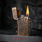 An ignited Gen 1 Single Claw lighter with hand-carved Earth Fissure texture, showing the mechanical spark and a tall flame against a dark, rustic background.
