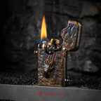 An ignited Gen 1 Single Claw Spirit Claw lighter, showing the mechanical gear spark and flame alongside its rugged hand-carved skeletal relief.