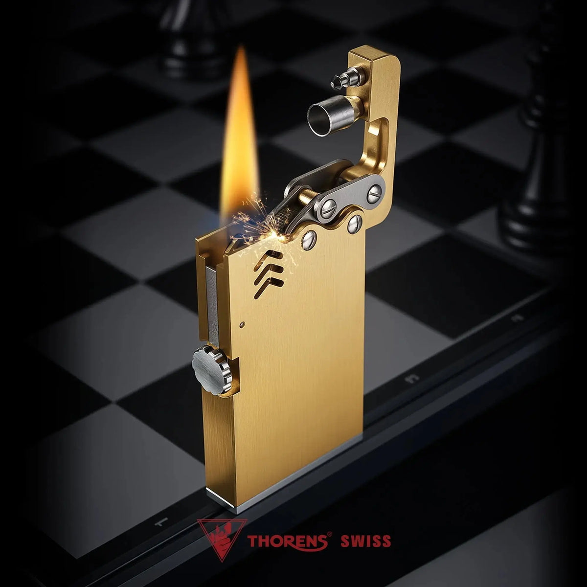 Thin Thorens ejection lighter in brushed brass shown during ignition with a steady flame, sparking flint, and open mechanical top arm.