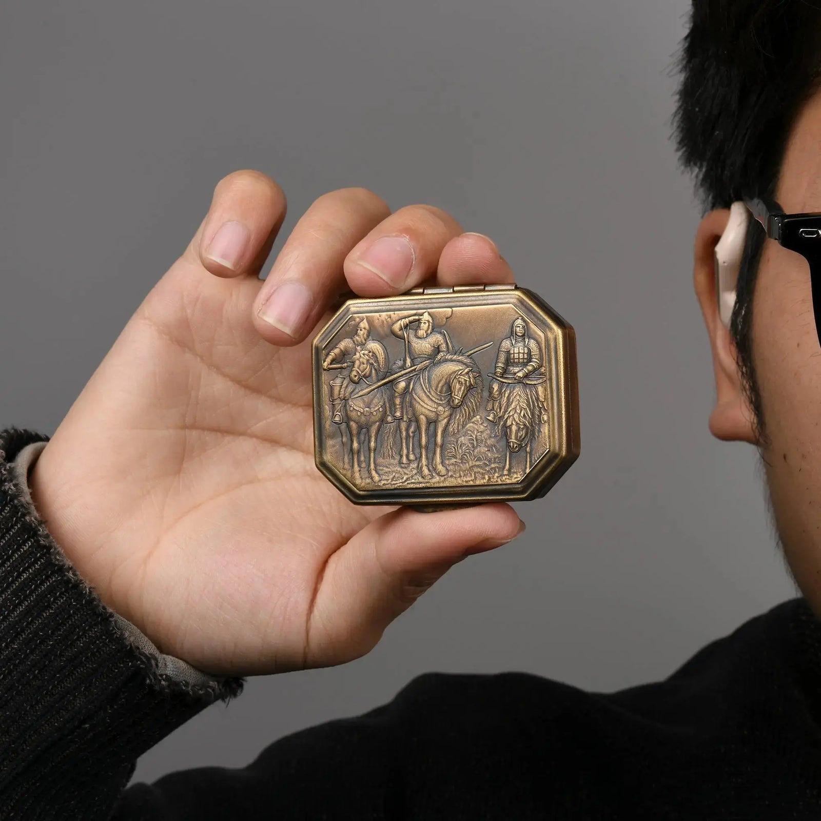 Thorens Knight’s Era matchbox lighter held in hand, showing the engraved medieval scene on the brass case and its compact collectible form against a neutral background
