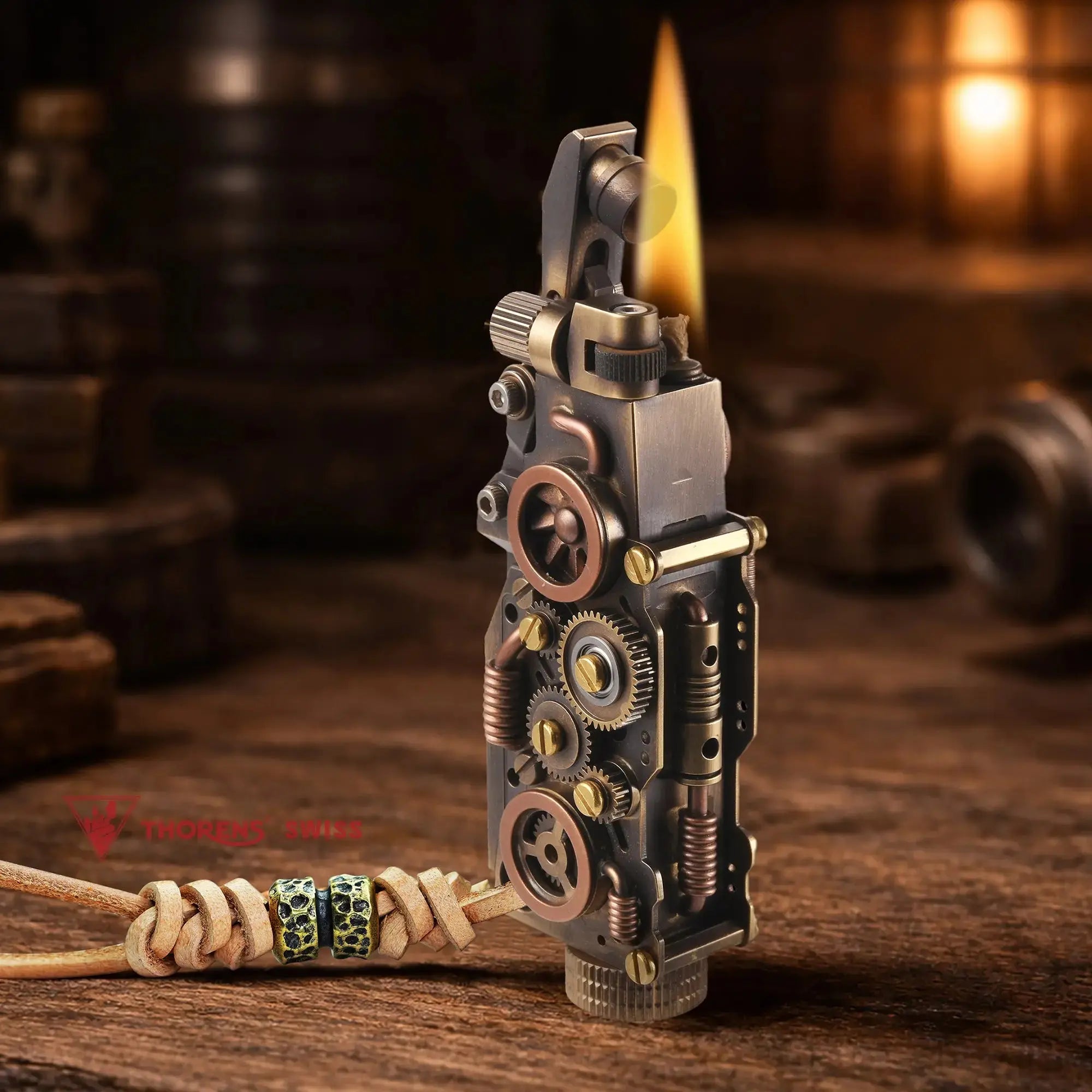 Thorens steampunk mechanical grip lighter in antique bronze shown lit on a warm wood surface, featuring exposed fine gears, articulated mechanical structure, and a leather lanyard with bead accents