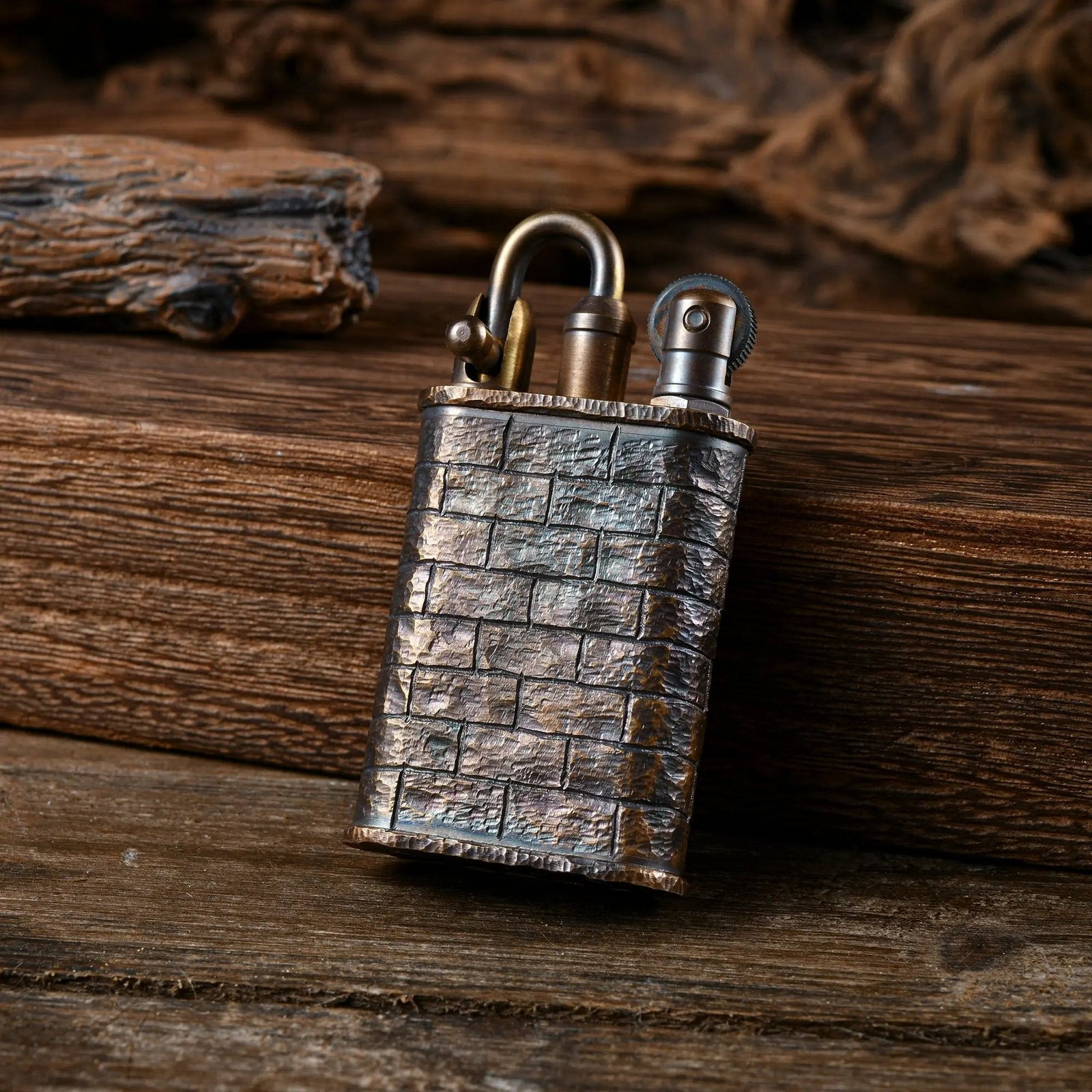 A Thorens Lockflame lighter featuring a hand-carved brick wall texture on its brass body, displayed on a rustic wooden surface to highlight its mechanical heritage.