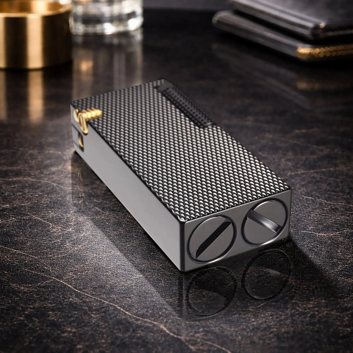 Thorens Slim Cube Black Mesh lighter resting on a reflective dark surface, featuring a slim rectangular form, black mesh texture, dark-toned body, and gold-tone accent detail