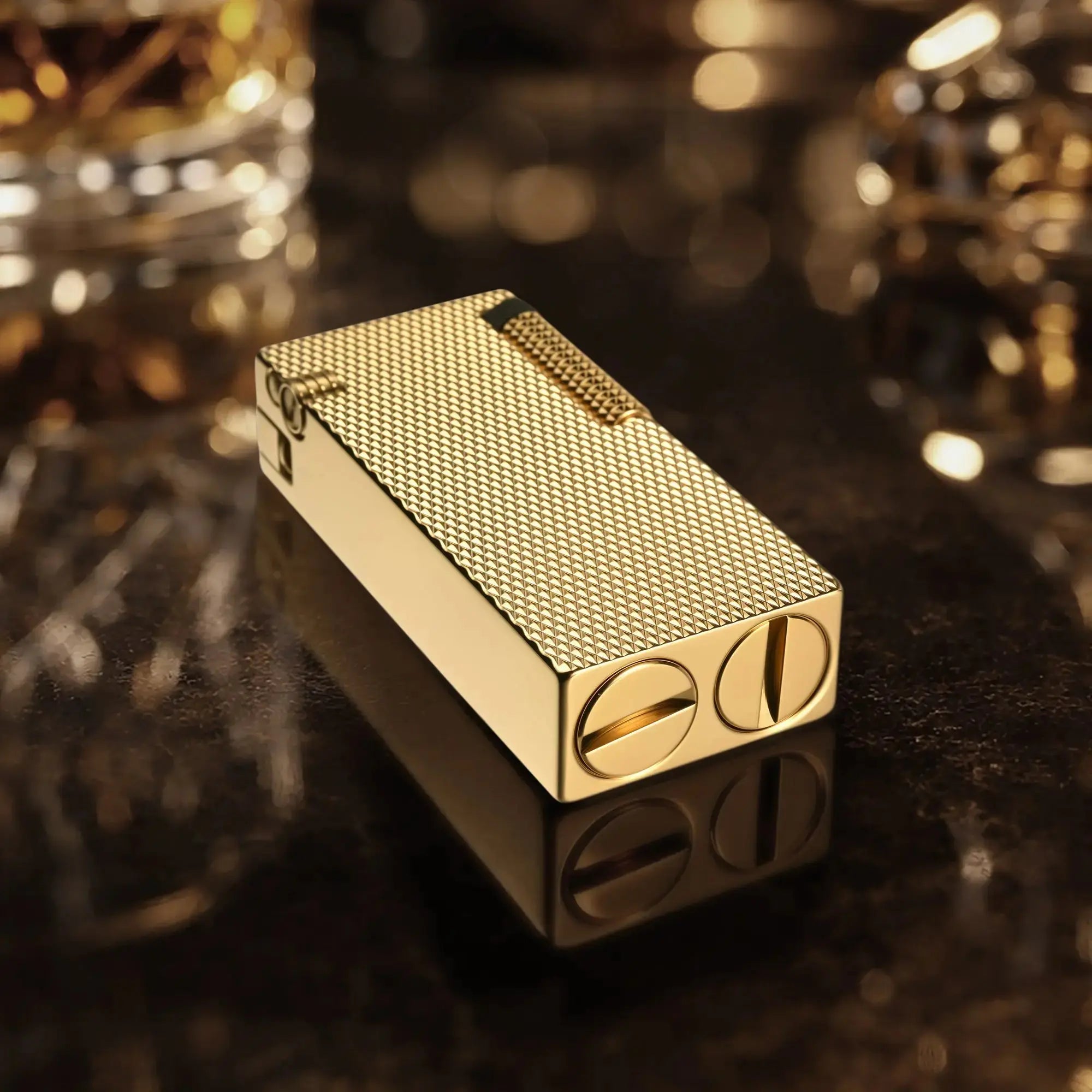 Thorens Slim Cube Golden Mesh lighter resting on a reflective dark surface, featuring a slim rectangular form, golden mesh texture, polished gold-tone body, and refined mechanical detailing