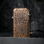 A vertical shot of the Gen 1 Single Claw lighter, highlighting the intricate hand-carved Earth Fissure texture on its weathered brass body, standing on a dark stone surface.