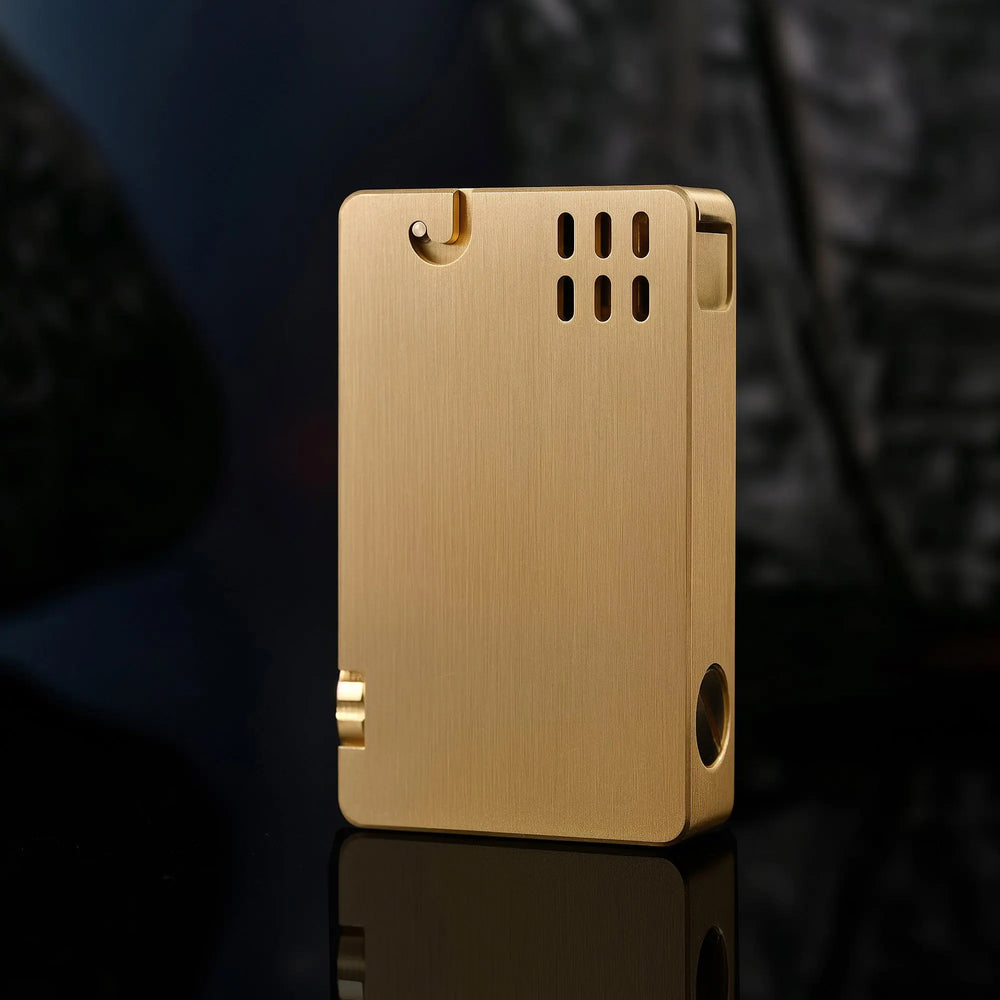 A closed ASPREY lighter featuring a brushed brass finish, vertical ventilation slots, and a sleek rectangular body with refined mechanical details.