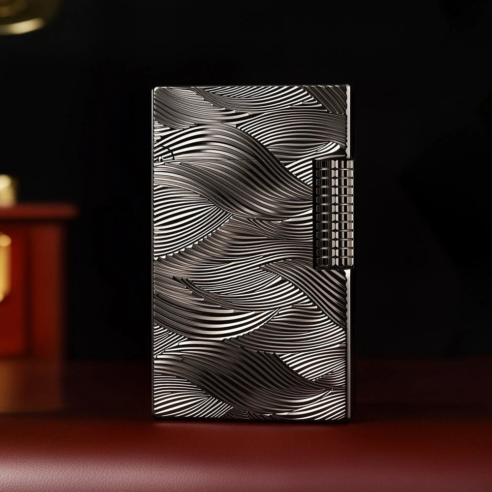 A front-facing shot of the Aqua Rhythm black lighter, featuring striking silver wave engravings against a dark chrome finish with a textured mechanical roller.