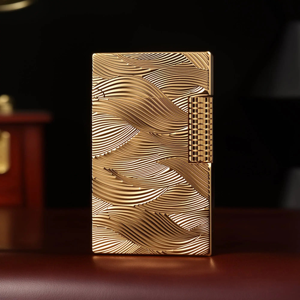 A front-facing view of the gold Thorens Aqua Rhythm lighter, showcasing the dense, overlapping wave engravings that cover the entire brass surface, accented by a square-knurled side-roller.