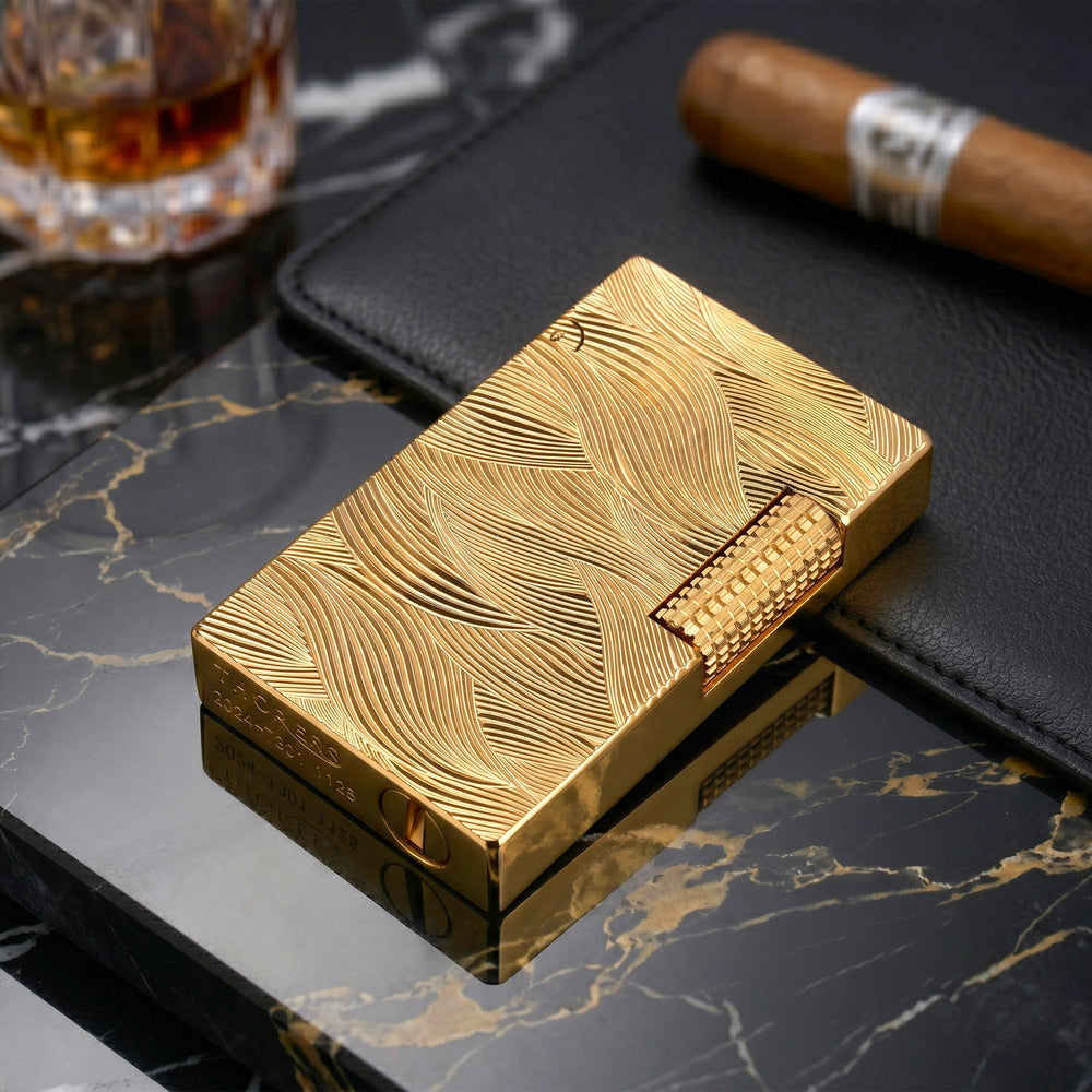 A front-facing view of the gold Thorens Aqua Rhythm lighter, showcasing the dense, overlapping wave engravings that cover the entire brass surface, accented by a square-knurled side-roller.