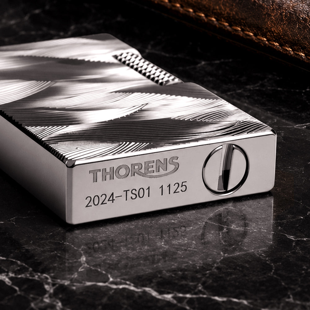 A close-up view of the Aqua Rhythm silver lighter standing upright, featuring a polished chrome finish with fluid wave engravings and a textured roller.