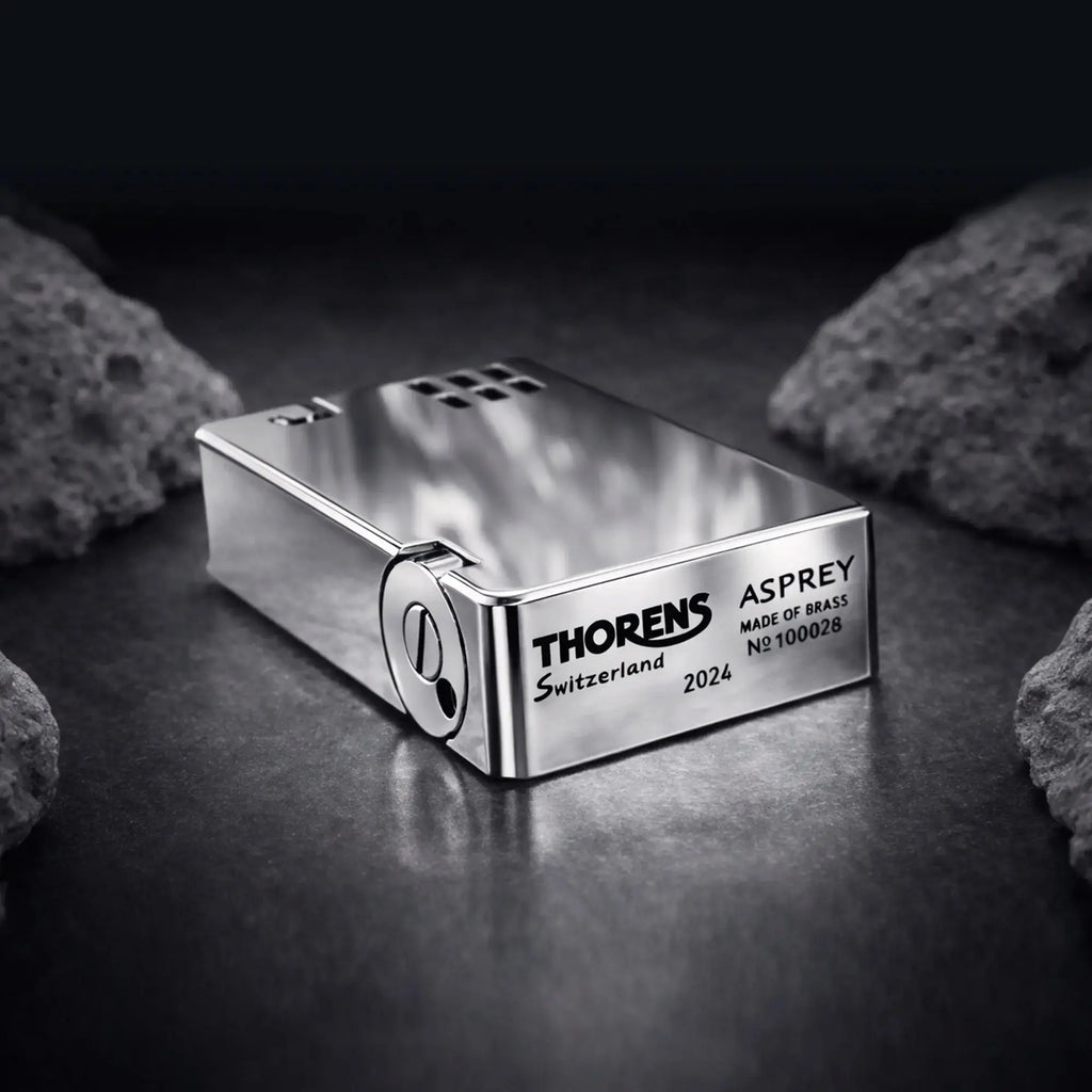 A close-up of the Thorens Asprey lighter in a polished silver finish, highlighting the "Thorens Switzerland" and "Asprey Made of Brass" hallmark engravings on the precision-milled base.