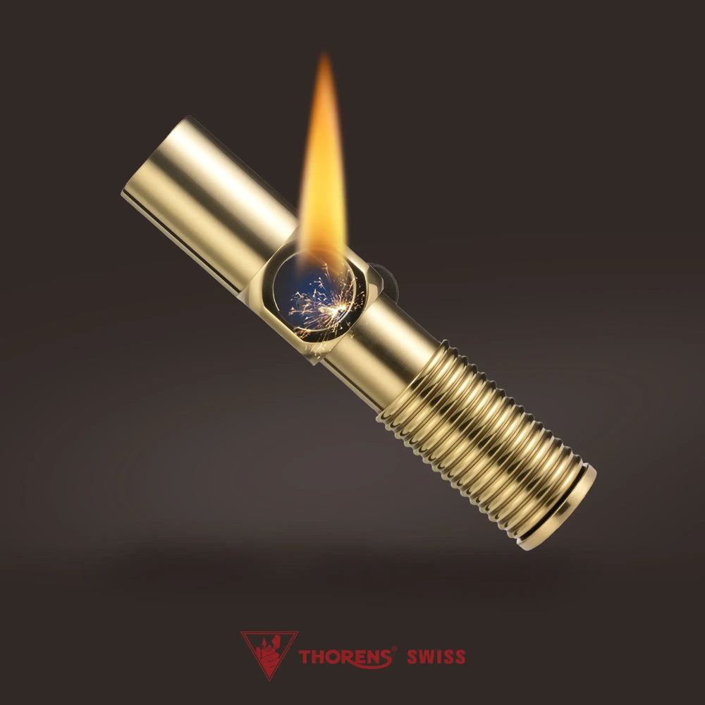 An ignited Big Screw Trench Lighter in polished brass, showing a vibrant flame and mechanical sparks within the hex-nut housing, set against a dark gradient background with the Thorens Swiss logo.