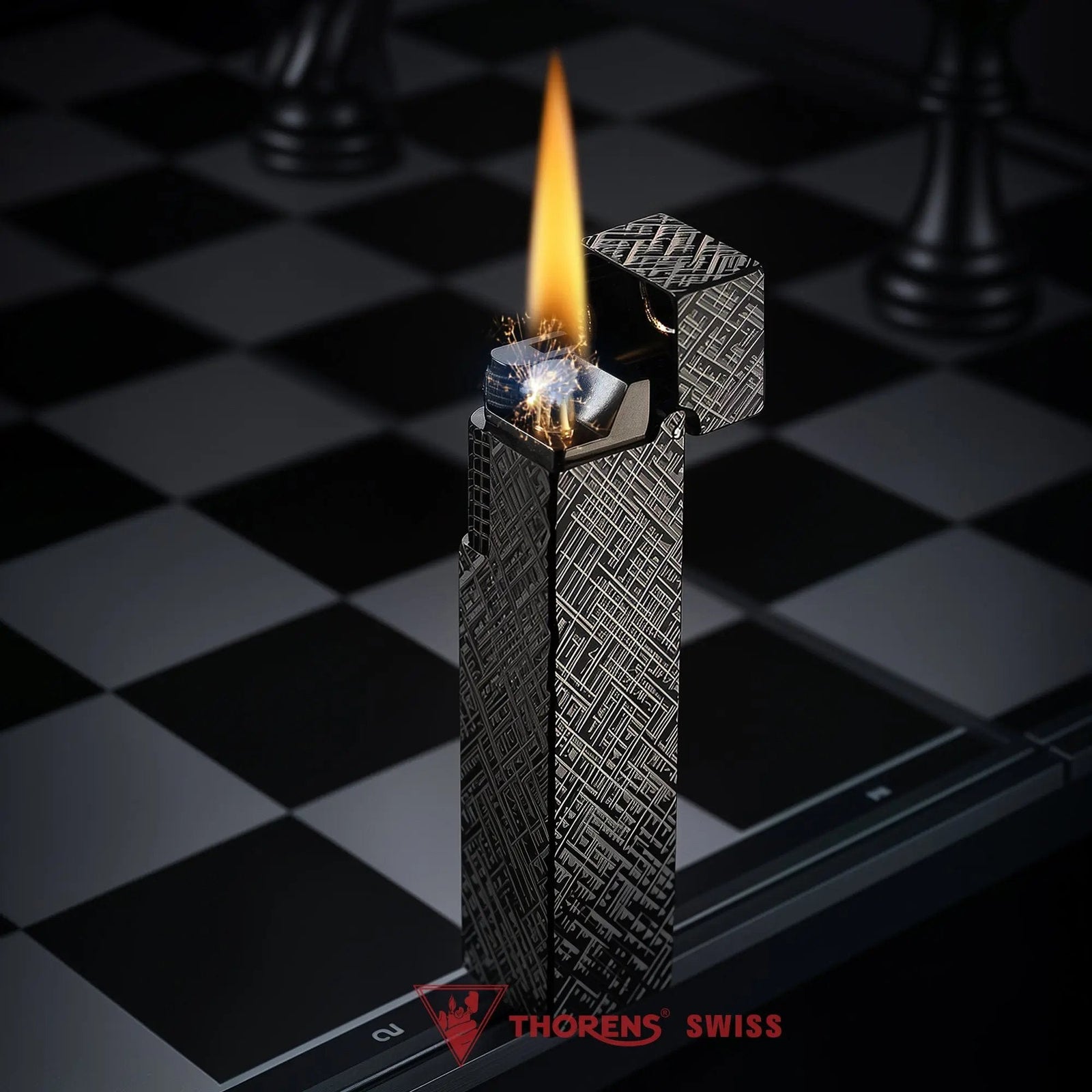 Black carved Thorens rectangular side-slip lighter standing upright with the lid open and flame lit, featuring an engraved geometric texture, exposed ignition wheel, and visible wick on a black and white checkered surface