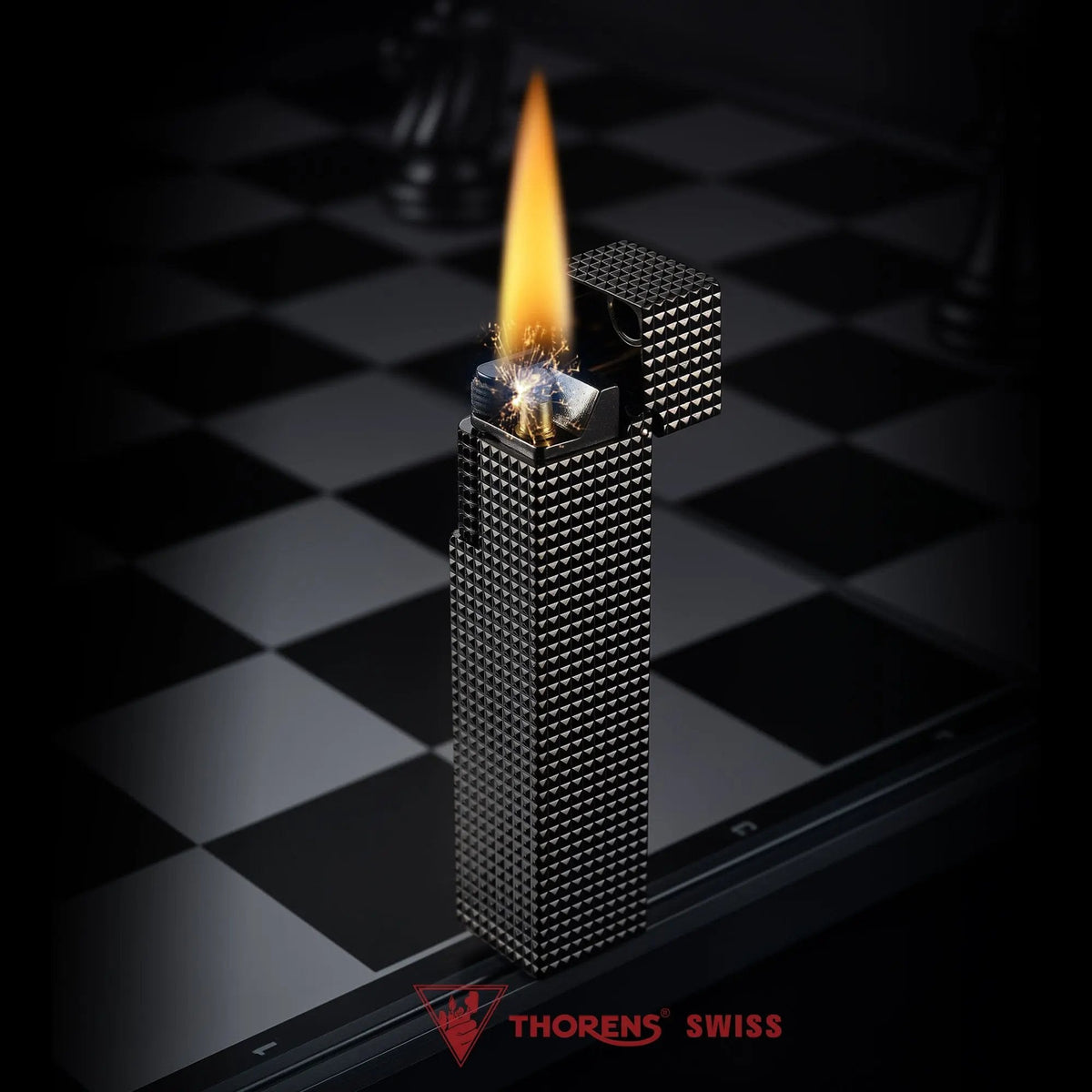 Lit black small square textured Thorens side-slip rectangular lighter standing open on a black and white checkerboard surface