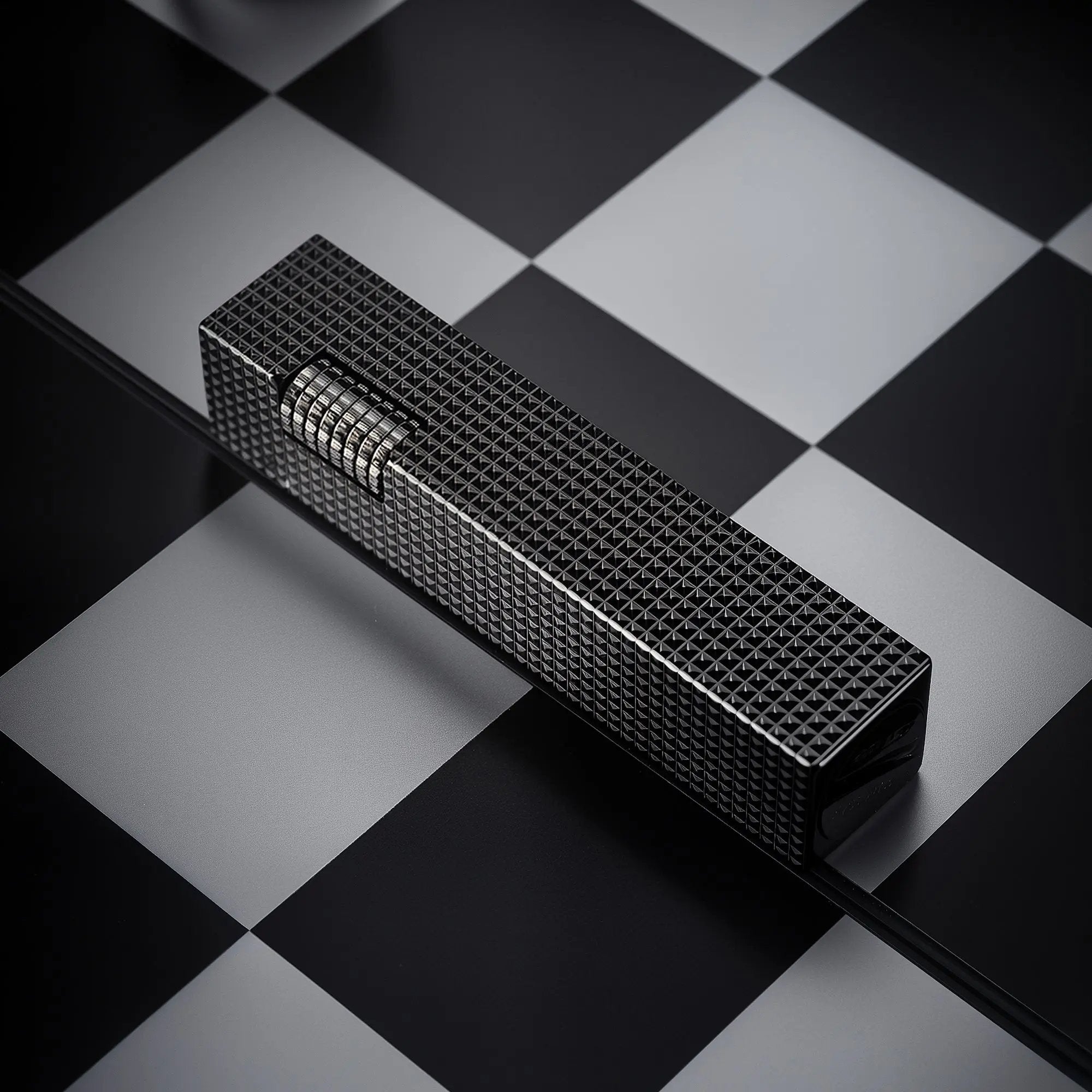 Black small square textured Thorens side-slip rectangular lighter placed on a black and white checkerboard surface