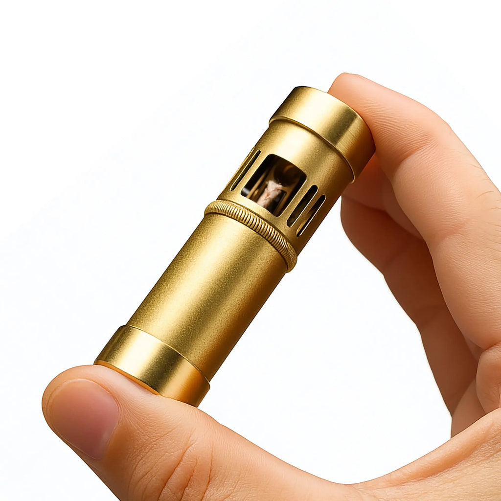 A close-up of the Thorens Blaze Capsule lighter being held, showcasing the windproof chimney, cotton wick, and the tactile knurled grip ring in a vintage brass finish.