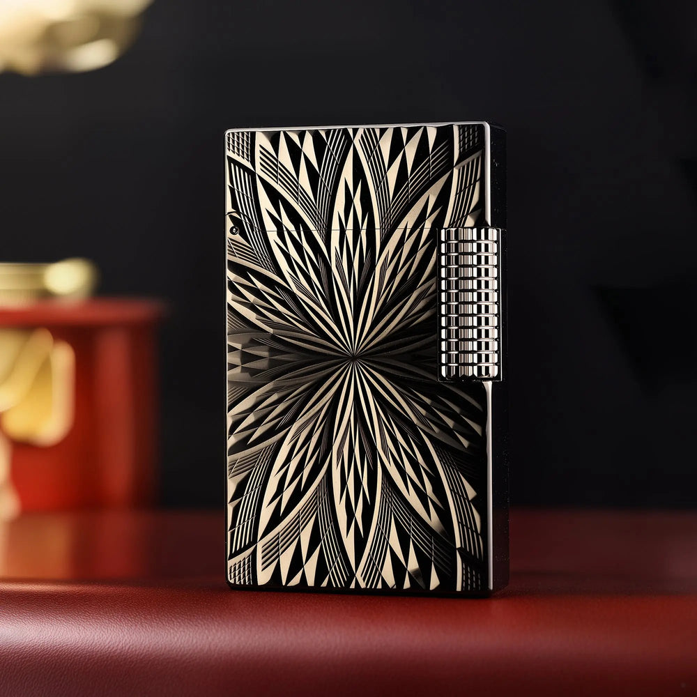 A front-facing view of the Blooming Radiance black lighter, featuring a symmetrical sunburst floral engraving on a polished dark brass body with a side roller.