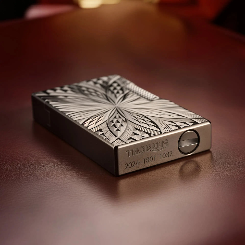 An ignited view of the Thorens Blooming Radiance black brass lighter with its open lid, showing a steady flame and spark, resting on a leather surface.