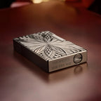 An ignited view of the Thorens Blooming Radiance black brass lighter with its open lid, showing a steady flame and spark, resting on a leather surface.