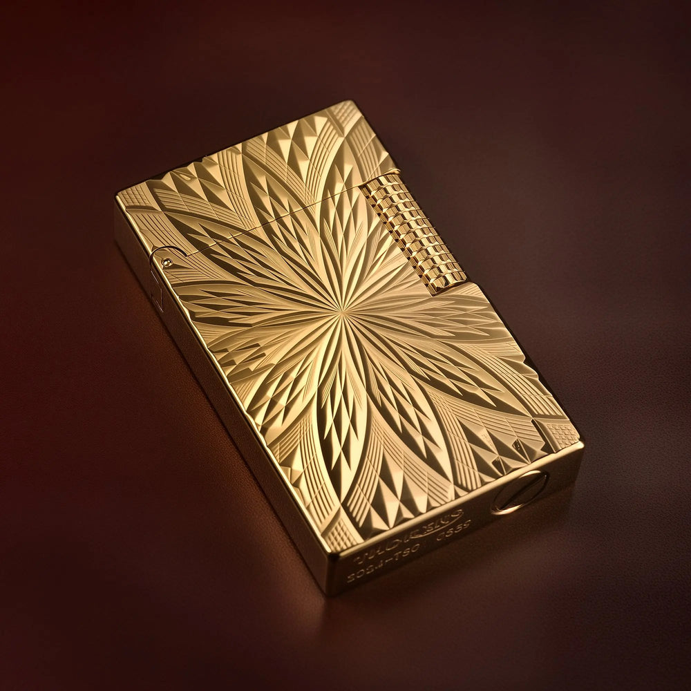 A Thorens Blooming Radiance gold-plated lighter resting on a dark leather surface, showcasing the deep-etched floral geometry and high-polish finish under warm lighting.