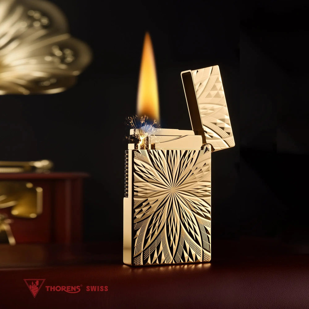 An ignited Blooming Radiance gold-plated lighter with an open lid, showcasing a warm, steady flame and mechanical sparks against the brilliant, floral-engraved gold body.