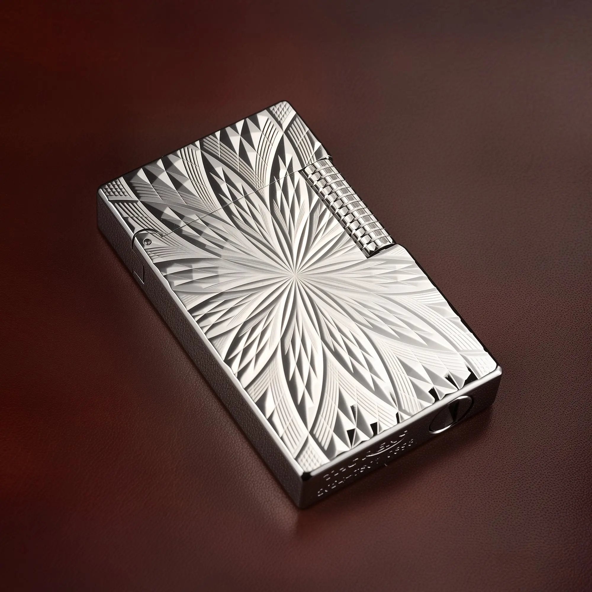 A Thorens Blooming Radiance silver-plated lighter resting on a dark leather surface, highlighting the crisp, deep-etched floral geometry and brilliant metallic luster.